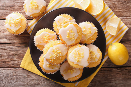 Sweet lemon muffins with zest and icing sugar close-up on a plate. horizontal top view