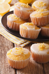 Homemade lemon muffins sprinkled with zest close-up on a plate. vertical