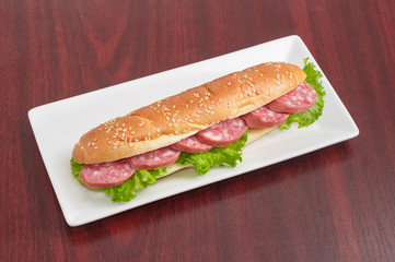 Sandwiches made with bun, sausage and lettuce on rectangular dish