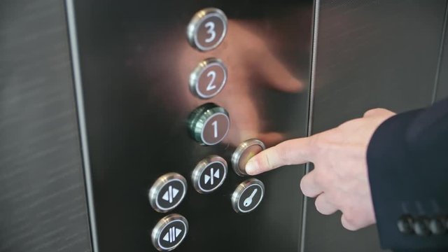 Close-up of forefinger pressing alarm button in office building elevator