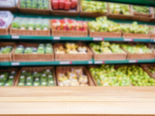 Wooden empty table in front of blurred supermarket fruits shelf