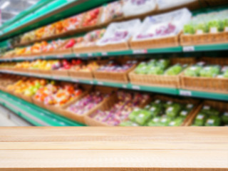 Wooden empty table in front of blurred supermarket fruits shelf