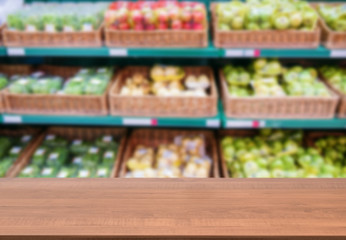 Wooden empty table in front of blurred supermarket fruits shelf