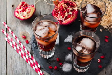 Pomegranate juice with ice in a glass on the old wooden background. Selective focus.