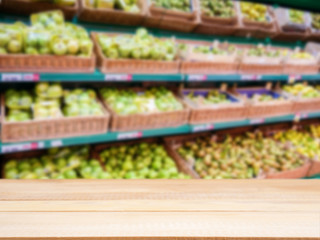 Wooden empty table in front of blurred supermarket fruits shelf