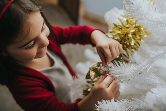 Small smiling girl decorating Christmas tree