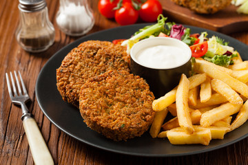 Serving of falafel and chips served on a black plate with sauce.