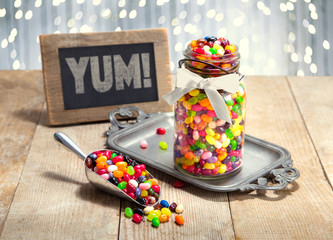 Yum sign next to candy filled jar and scoop of multi color assorted jelly beans on a party table