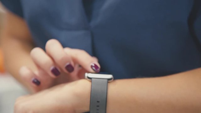Woman using her smartwatch touchscreen wearable technology device. Young woman trying new smart watch. Smart watch. Woman Using Smart Watch and Smart Phone. Closeup. Smart watch on female wrist
