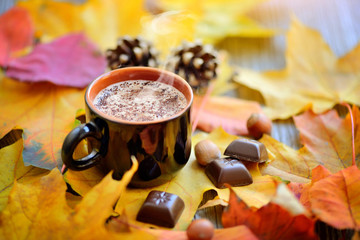Autumn Cup of coffee, nuts, pine cones, chocolate and autumn leaves. Autumn background. Autumn scene. Coffee and autumn leaves.