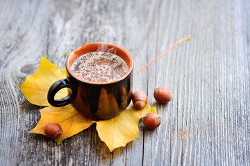 Coffee cup on the autumn fall leaves and wooden surface background