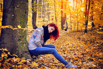 Red-haired girl walking in the autumn forest