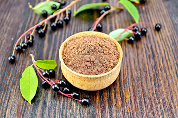 Flour bird cherry in bowl with berries and leaves on board
