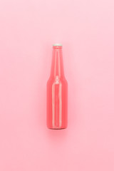 glass bottle of pinkish soda drink on pink background
