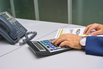 Businessman counting on calculator at the office