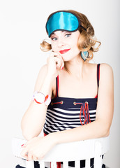 beautiful young woman in a striped dress and points for sleep, sitting on a chair and posing. sleeping eye covering mask