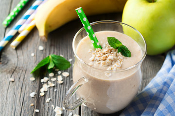 Apple banana smoothies with oatmeal on the old wooden background. Healthy breakfast. Selective focus.