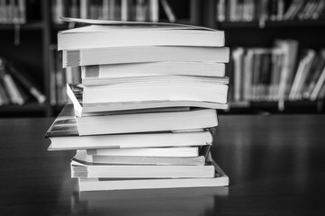 Black and white pile of books in a library and bookshelf