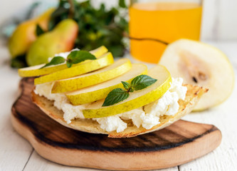 Bruschetta with soft cheese, juicy pear and a glass of fresh juice. Eco breakfast. Fitness menu. Close-up.