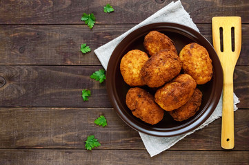 Meat mini-rolls (cutlet) with boiled egg in a clay bowl on dark wooden background. The top view.