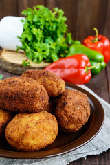 Meat mini-rolls (cutlet) with boiled egg in a clay bowl on dark wooden background.