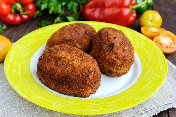 Meat mini-rolls (cutlet) with boiled egg in a clay bowl on dark wooden background.