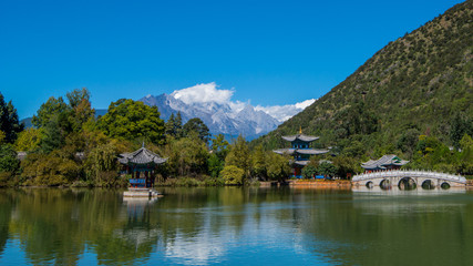 Fototapeta na wymiar Black Dragon Pool to the Five Phoenix Tower and the Five Holes Bridge. In the background is Jade Dragon Snow Mountain. The Old Town of Lijiang is located in Lijiang City, Yunnan, China.