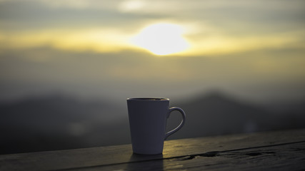 Cup with tea on table over mountains landscape with sunlight. Beauty nature background