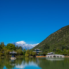 Black Dragon Pool to the Five Phoenix Tower and the Five Holes Bridge. In the background is Jade Dragon Snow Mountain. The Old Town of Lijiang is located in Lijiang City, Yunnan, China.