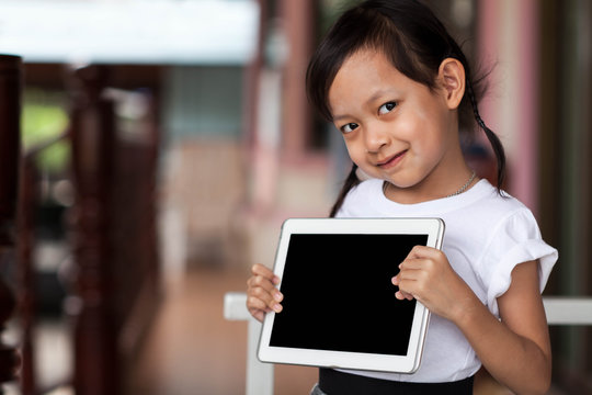 Happy child playing  tablet or small computer at home.Black blan