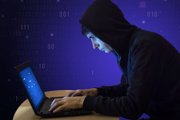 Hacker with laptop initiating cyber attack