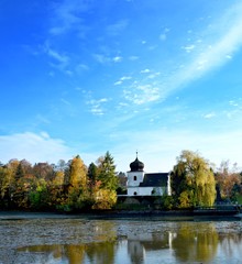 Obraz premium The church at pond with reflection in water and blue sky.