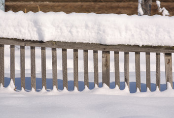 Snowy fence in the countryside. The snow sparkles in the sun. Ru
