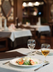 Caesar salad with shrimps in the interior of the restaurant