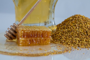 Honeycomb on a table with honey in a jar a wooden dipper and bee pollen granules 1