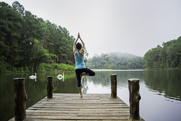 Fototapeta na wymiar Young healthy woman practicing yoga on the bridge in the nature