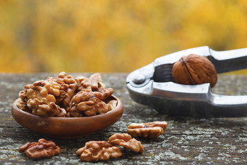 Walnut kernels in wooden bowl  and nut cracker on old, rustic table