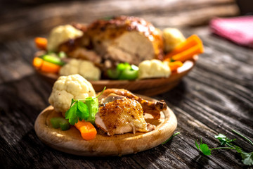 Whole roasted chicken with vegetables on wooden background