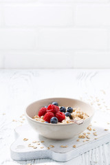 homemade oatmeal with berries on white wooden board, vertical