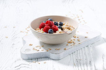 homemade oatmeal with berries on white wooden board