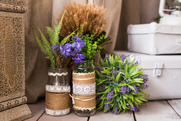 Rustic still life: dried flowers bunch and vases on vintage wooden background.