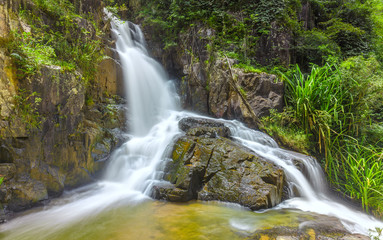 Fototapeta premium Landscape waterfall flowing into soft silk sheet in the forest create the beauty of the natural world in the wilderness.