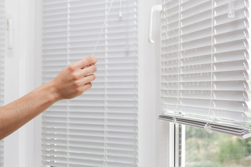 Adjusting the white blinds in height use a cord