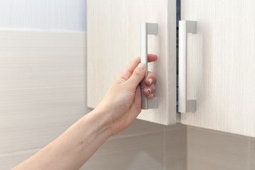 Female hand open the cupboard doors, close up