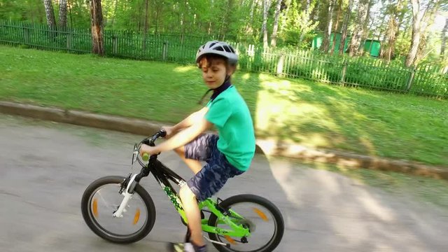 Happy young boy riding bike in sunny day