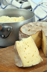 Tomme de Savoie avec une casserole d'aligot à l'arrière plan