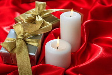 Gift boxes and candles on red satin