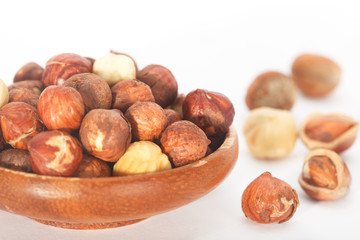 Hazelnuts in a wooden bowl isolated on white background.