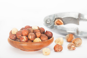 Hazelnuts in a wooden bowl with nut cracker. White background.