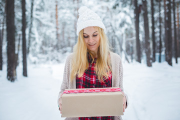 girl holding a Christmas gift in winter forest